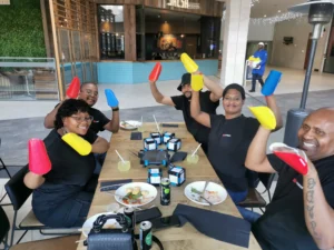 Contact Us to enjoy team building like this fun group from DB Schenker raising red and yellow paper hands during a team building challenge at Bedford Centre