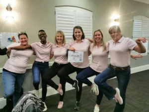 A fun group of women from SEW-Eurodrive wearing matching pink shirts and posing playfully during a team building event at Gold Reef City